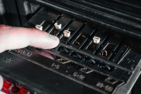 Finger pointing at exposed automotive fuse slots during electrical testing
